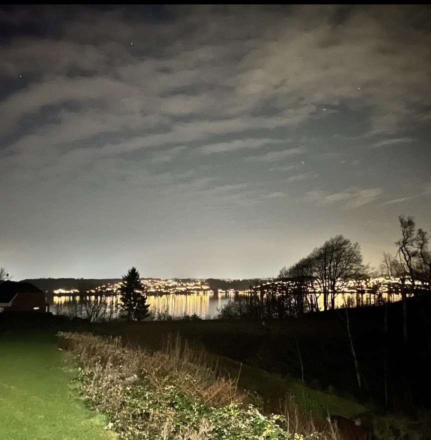 Aftenudsigt over Vejle Fjord fra ejendommen — byens lys spejler sig i fjorden